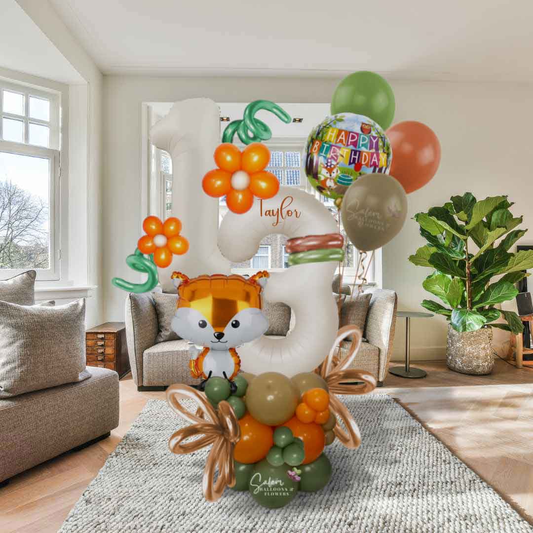 A Woodland themed balloon bouquet with a large balloon number, in a green, orange and beige color palette. Featuring a cute Fox shaped balloon standing in a Living Room. Balloons Salem Oregon